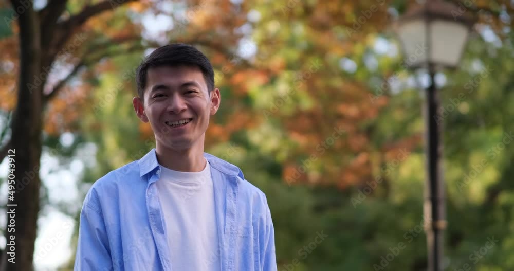 smiling handsome Asian young man at forest in autumn. Looking at camera. Slow motion smiling handsome Asian young man at forest in autumn. Looking at camera. Slow motion