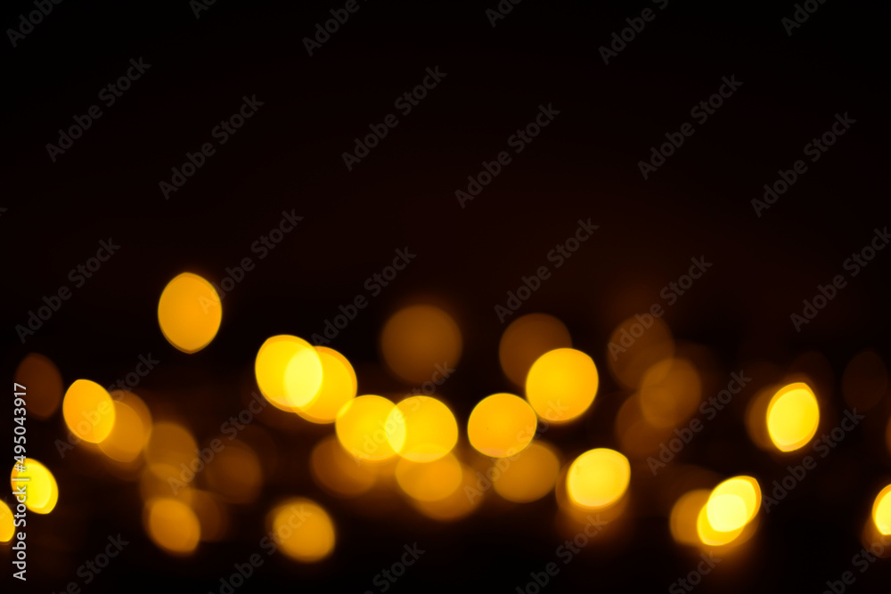 Golden glitter bokeh lights on a black background, unfocused. Holiday, party or birthday background
