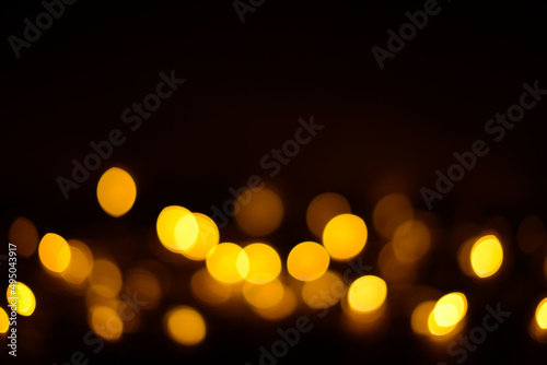 Golden glitter bokeh lights on a black background, unfocused. Holiday, party or birthday background © maxa0109