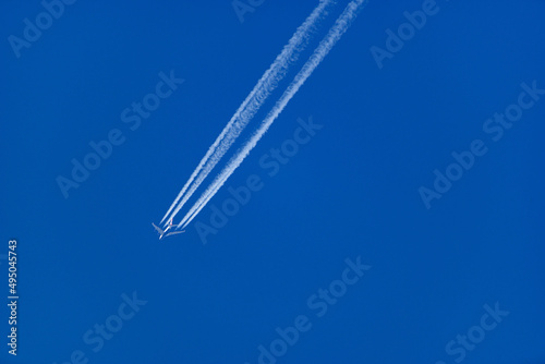 four engine jet aircraft flying in the sky with contrail