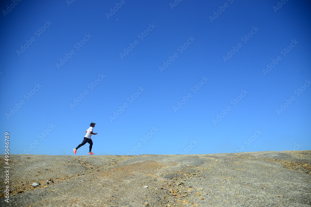 A man in a white shirt is jogging against a beautiful blue belly background.