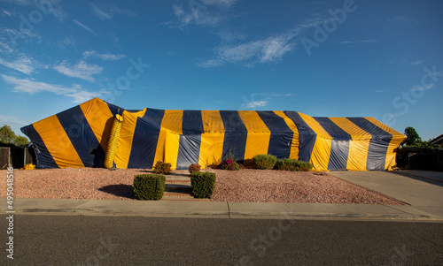 Ranch style House covered in yellow and blue termite tent photo