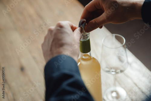 Sommelier bartender prepares drop saver bottle of white wine for guests to pour