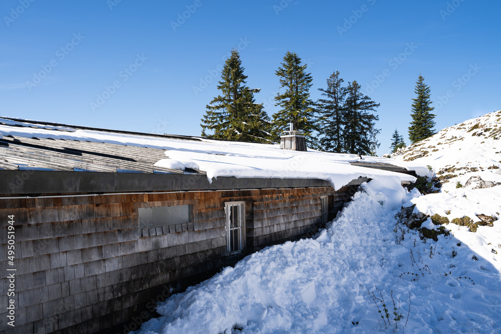 Snowy wooden hut in the mountains on a warm day in winter with blue sky Snowy wooden hut in the mountains on a warm day in winter with blue sky