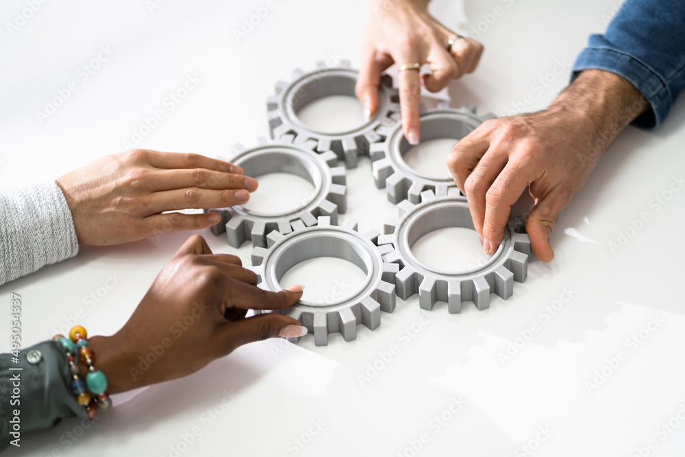Group Of Businesspeople Joining Together Gears On Table