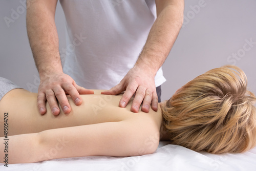 The osteopath works with the spine. A teenage child lies on a couch in front of a doctor. A chiropractor examines the spine. Posture correction © dewessa