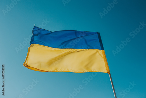 The flag of Ukraine is a large national symbol flying in the blue sky. Large yellow and blue state flag of Ukraine.