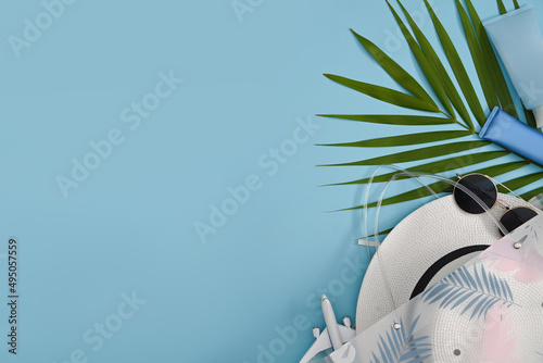 Flat lay traveler accessories and tropical palm leaves on blue background with copy space. Travel, summer and holiday concept.