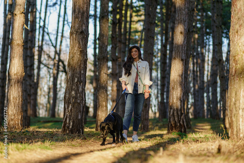 A smiling young attractive woman playing and walking with her Labrador puppy in a city park. The concept of pet and animal care.