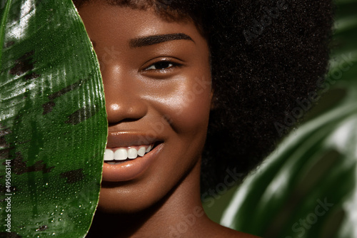 Photography African American young woman smilling, close up potrait against green tropacal leaf