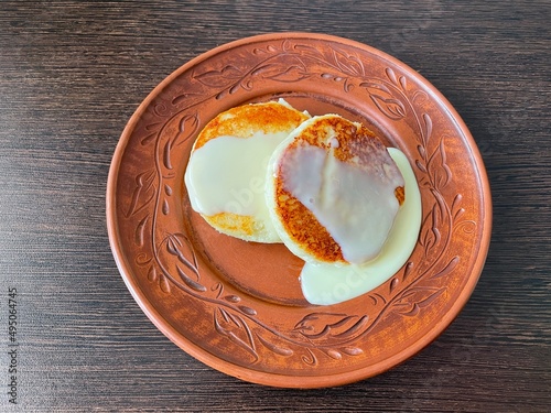 large horizontal photo. Homemade food. brown clay plate on a brown wooden table. top view close-up. two fried cheesecakes with condensed milk. healthy wholesome food. eco. bio. curd breakfast.