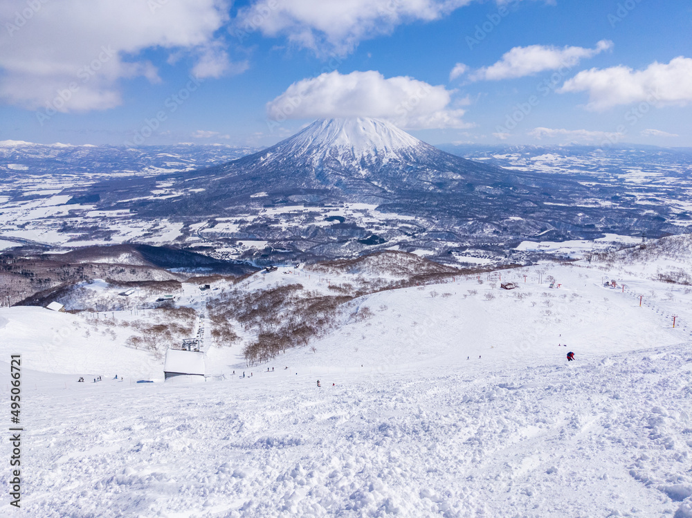 Overlooking at slopes and a snowy volcano from a off-piste area of mountaintop in a ski resort (Niseko, Hokkaido, Japan)