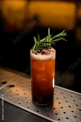 glass of cocktail with pine cones decorated with a rosemary branch