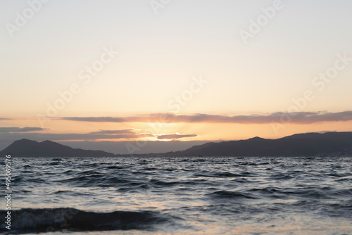 A summer sunset at sea with mountains in the background.