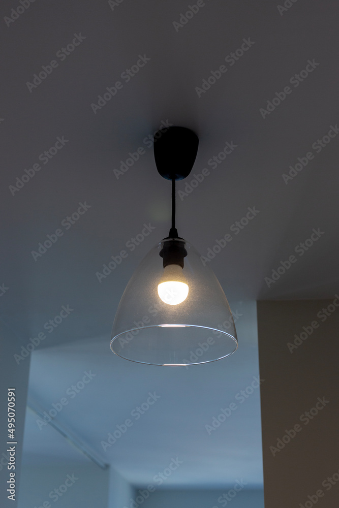 Lamp with glass shade on the ceiling in the room