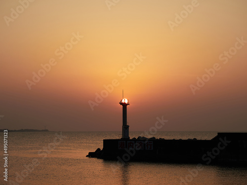 3月（春） 夕暮れ時、防波堤灯台に重なった太陽 宮崎漁港（富山県朝日町）