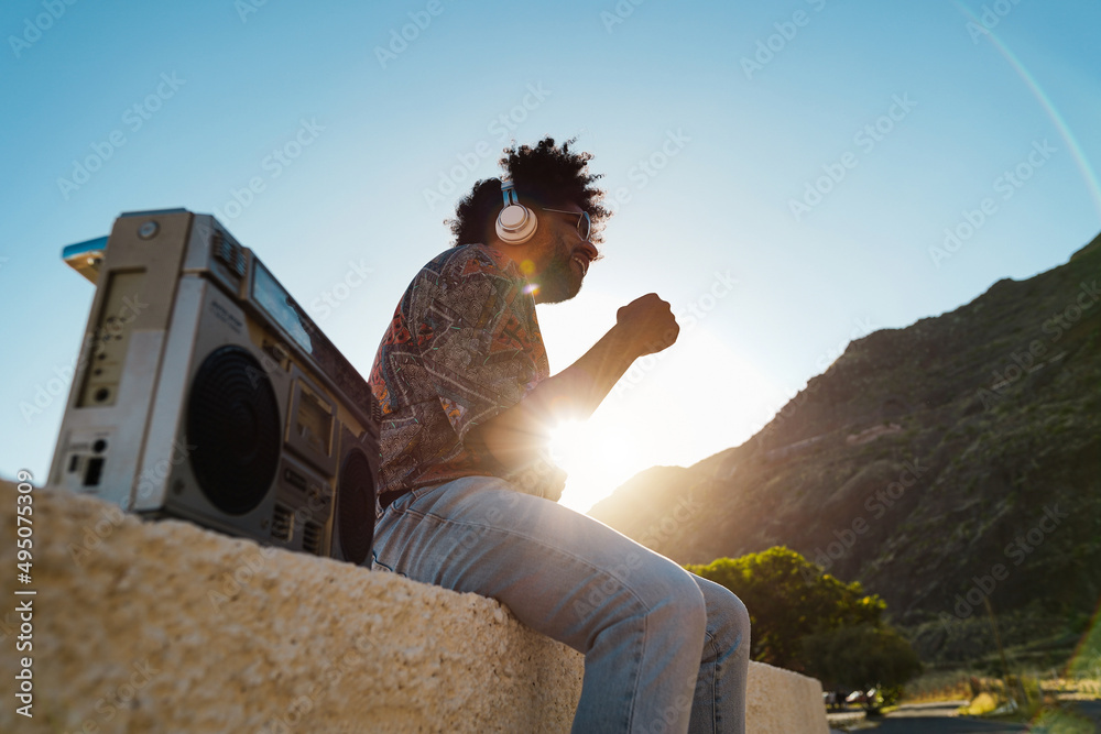 African american man listening music with vintage boombox stereo outdoor - Focus on headphones - obrazy, fototapety, plakaty 