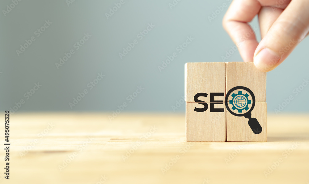 SEO, Search Engine Optimization ranking concept.  Digital marketing strategy of promote traffic to website. Hand holds wooden cubes with the icon of magnifying glass with alphabets abbreviation SEO.