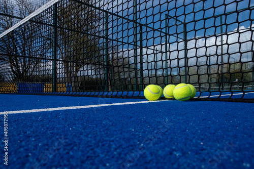 selective focus, five balls near the net of a blue paddle tennis court © Vic