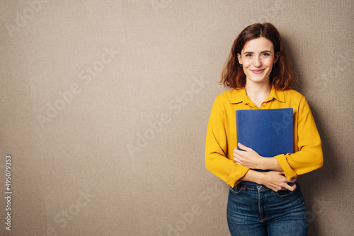young business woman with resume stands in front of brown background