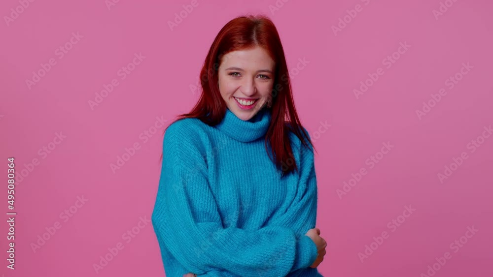 Cheerful beautiful teenager student girl in blue sweater smiling and looking at camera. Young fashion lovely model woman indoors studio shot isolated on pink wall background. Female nature beauty Cheerful beautiful teenager student girl in blue sweater smiling and looking at camera. Young fashion lovely model woman indoors studio shot isolated on pink wall background. Female nature beauty