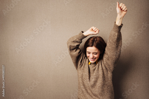 young happy celebrating business woman against brown background