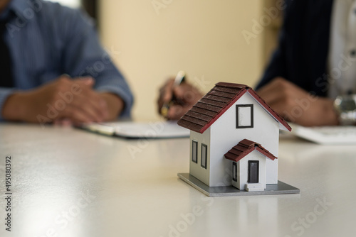 The real estate agent negotiates, discusses the terms of the home purchase contract, and asks the client to sign a contract with the home ode, contract documents, and calculator on the table.
