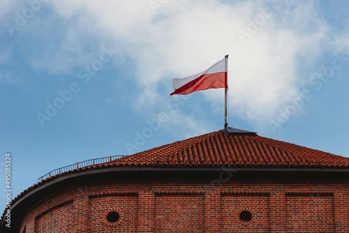Flag of Poland waving in the wind against blue sunny sky background
