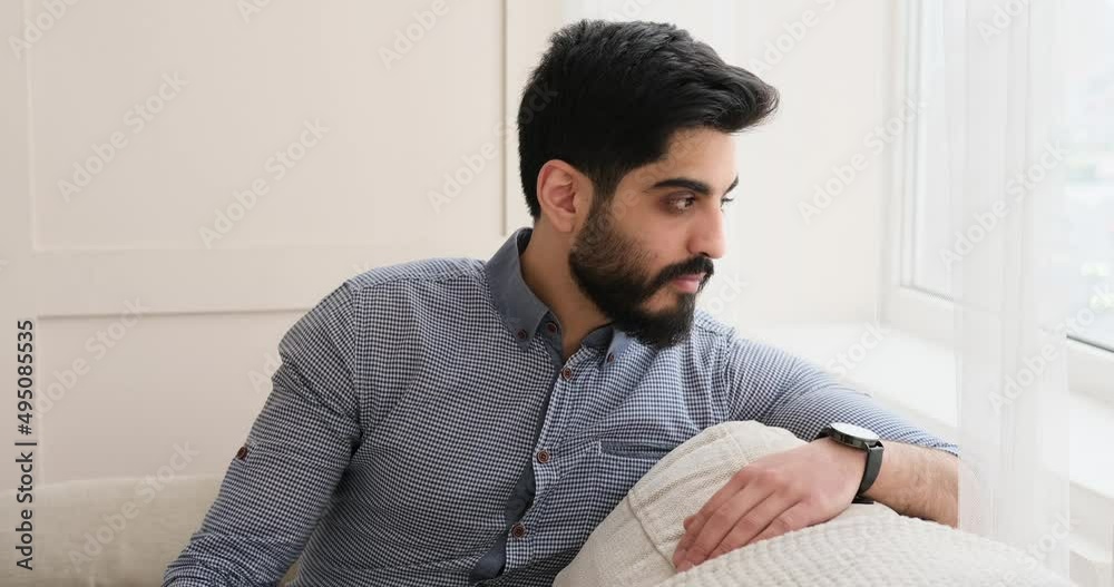 Young man sitting on sofa looking out through window Young man sitting on sofa looking out through window