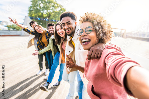 Multiracial friends group taking selfie pic with smartphone outside - Happy young people having fun walking on city street - Friendship concept with guys and girls enjoying summertime day outside photo