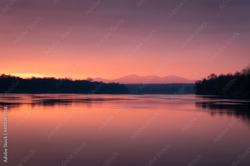 Dramatic sunset over Sava river with mountain in hazy glow - beautiful natural landscape
