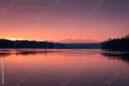 Dramatic sunset over Sava river with mountain in hazy glow - beautiful natural landscape