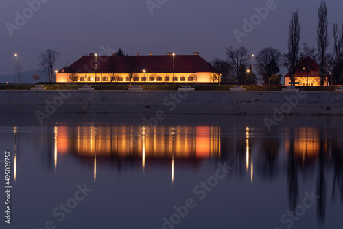 The illuminated building of the City Assembly in Slavonski Brod is reflected in the water of the Sava River at night in Croatia photo