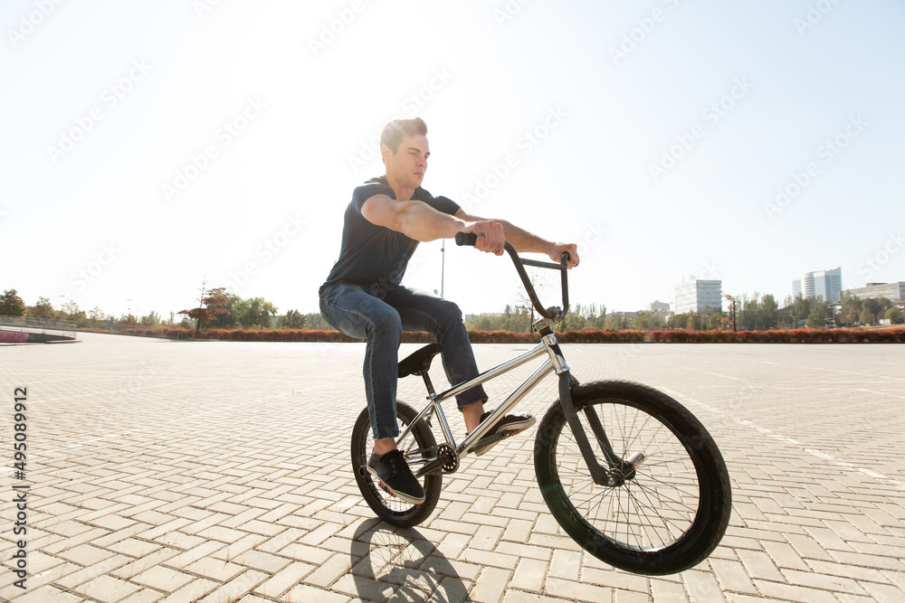 Street portrait of a bmx rider in a jump on the street in the background of the city landscape and the sun