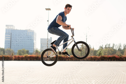 Street portrait of a bmx rider in a jump on the street in the background of the city landscape