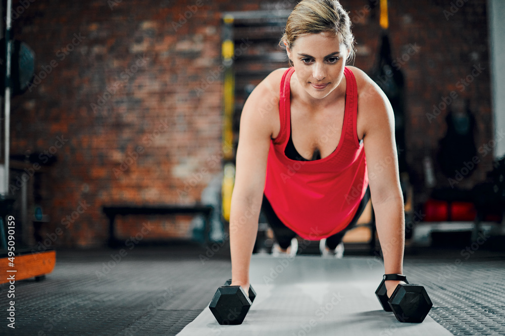 Total dedication. Full length shot of an attractive young female athlete working out with dumbbells in the gym.