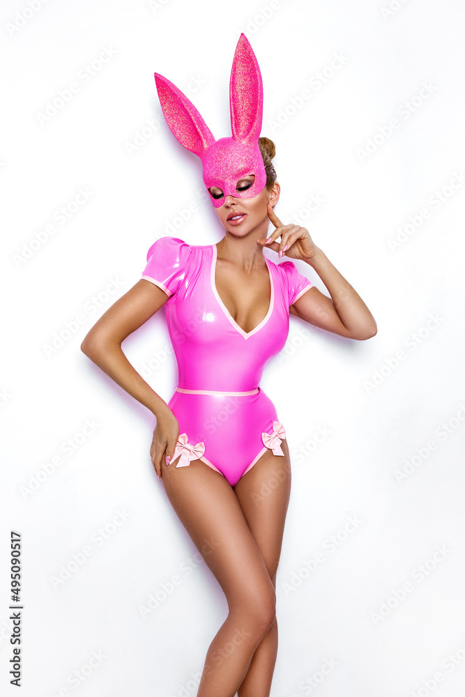 Sexy blonde woman posing in latex pink costume and pink bunny mask and pink  balloons on white background. Easter bunny concept. Latex lingerie. Naughty  girl. Halloween costume. Woman with balloons. Stock Photo