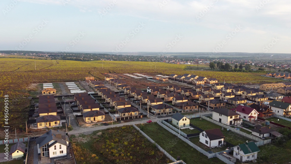 Aerial view of residential houses neighborhood and apartment building complex at sunset. Tightly packed homes, driveway surrounds green tree flyover in Ukraine. Suburban housing development