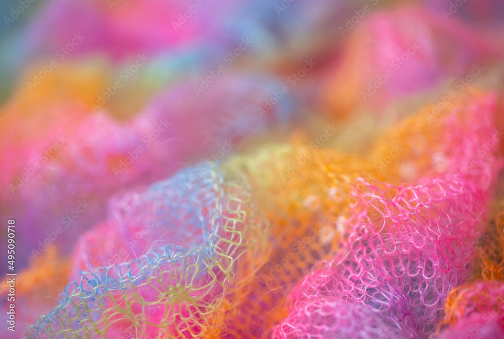 Fototapeta premium Knitted surface woolen items rainbow colored as a background. Closeup of soft multicolored knitted texture patterns. Warm winter clothes. Background textile surface with copy space for text. blurred