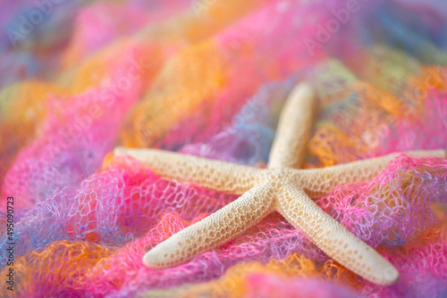 Knit surface of beachwear in rainbow color with starfish. Close-up of soft multicolored knitted patterns texture as background. Sea vacation  beach season.
