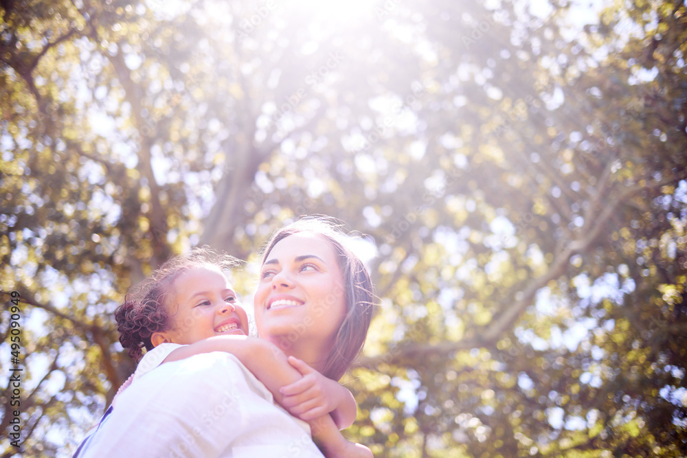 Spending time in the sun with you. Shot of a mother giving her daughter a piggyback ride in the park. Spending time in the sun with you. Shot of a mother giving her daughter a piggyback ride in the park.