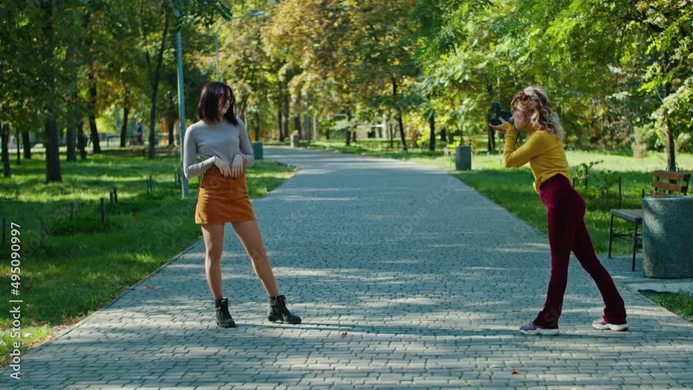 happy young girl posing against the backdrop of the city park to her friend photographer. youth and beauty.