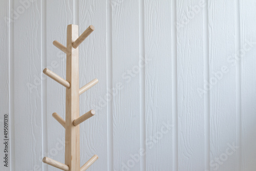 Wooden cloth hanger rack with white wall background copy space.