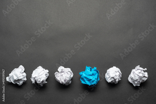 Crumpled blue paper ball among white balls