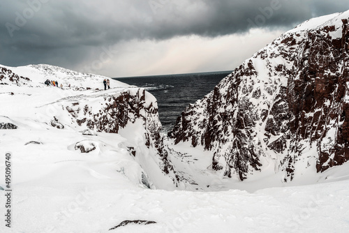 View on mountains covered with the snow near the sea in dramatic style