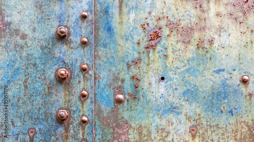 Grunge industrial background of worn metal with faced blue paint and rust spots joined by rivets and bolts