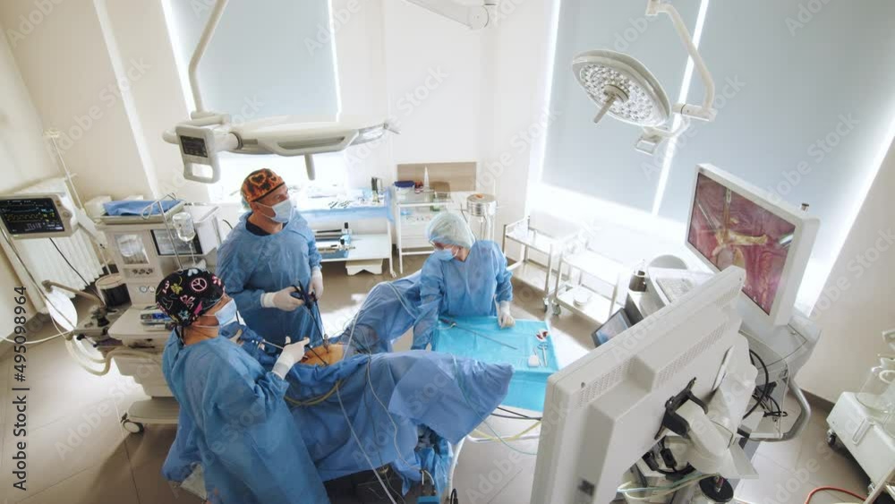 Surgeons team preforming operation in hospital operating theater, male surgeon operating patient,wearing surgical gown,operating room,,working with surgical laparoscopy instruments. Gynecology Surgeons team preforming operation in hospital operating theater, male surgeon operating patient,wearing surgical gown,operating room,,working with surgical laparoscopy instruments. Gynecology