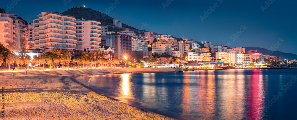 Illuminated quay on Ionian sea. Panoramic evening view of Saranda port. Colorful outdoor scene of Albania. Traveling concept background.