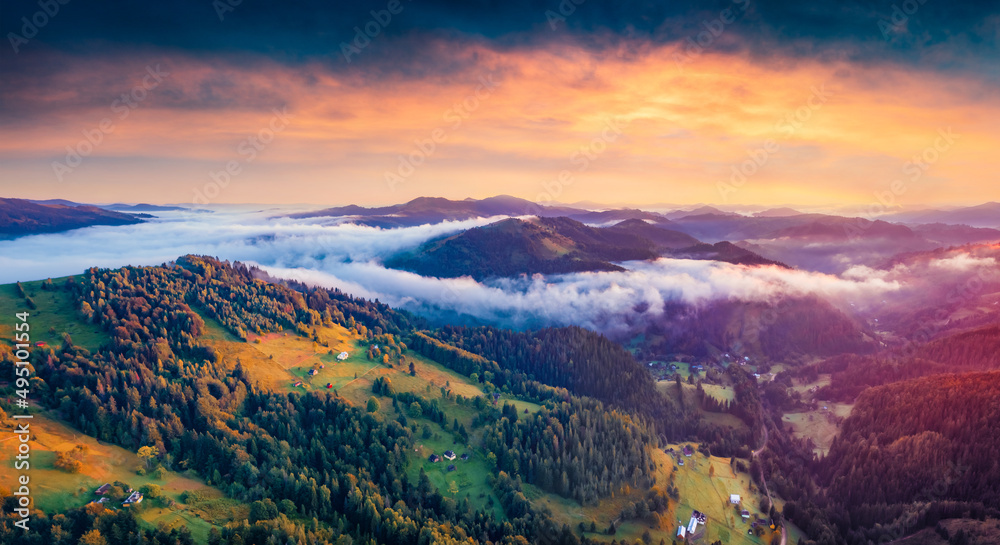 Majestic sunrise in Carpathian mountains. Fog spreads on the valley of Snidavka village, Ukraine, Europe. Picturesque summer landscape of mountain hills glowing by first sunlight.