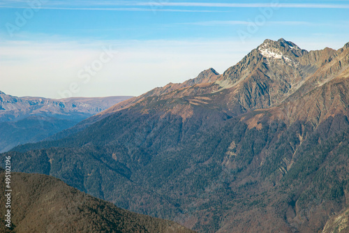 Beautiful landscape in the mountains with peaks against the blue sky and valleys covered with grass